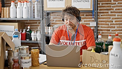 Young hispanic man volunteer writing on clipboard having video call at charity center Stock Photo
