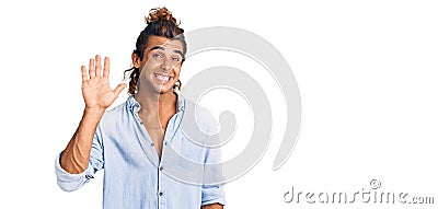 Young hispanic man wearing summer style waiving saying hello happy and smiling, friendly welcome gesture Stock Photo