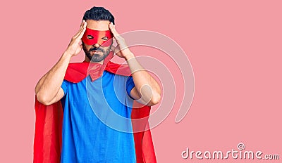 Young hispanic man wearing super hero costume suffering from headache desperate and stressed because pain and migraine Stock Photo