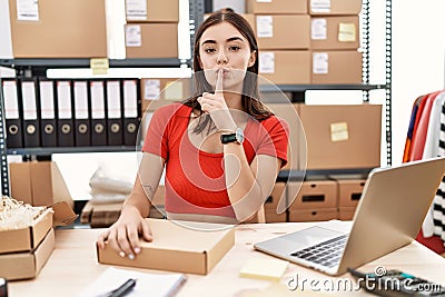 Young hispanic woman preparing order working at storehouse asking to be quiet with finger on lips Stock Photo