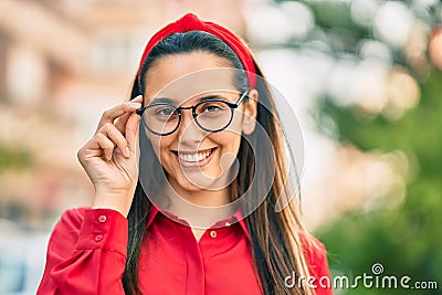 Young hispanic woman smiling happy touching his glasses at the city Stock Photo