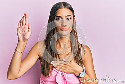 Young hispanic woman wearing casual style with sleeveless shirt swearing with hand on chest and open palm, making a loyalty Stock Photo