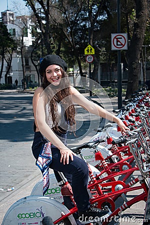 Young hispter lady using the street bikes of the mexican urban program EcoBici Editorial Stock Photo