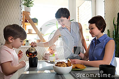 A young homosexual lesbian family with two children, a boy and a girl, at home in the kitchen forgiving the windows Stock Photo