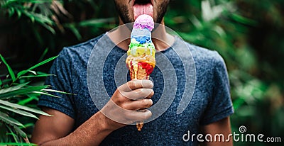 Young homosexual man sexy licking colourful lgbt rainbow symbol ice cream on a gay pride celebration. Lesbian, gay, bisexual, tran Stock Photo