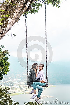 Young honeymoon couple swings in the jungle near the lake, Bali island, Indonesia. Stock Photo