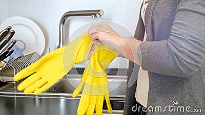 Young housewife protecting hands with yellow rubber gloves before doing house work Stock Photo