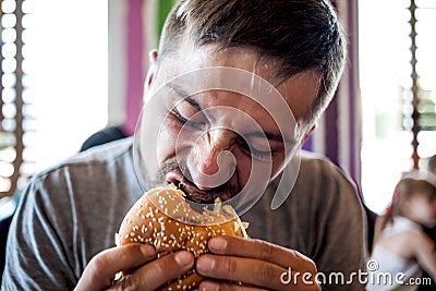 A young man eating a burger Stock Photo