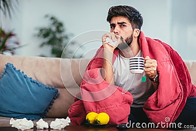 Ill man drinking hot tea at home and watching tv Stock Photo