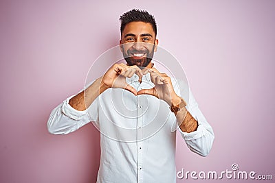 Young indian businessman wearing elegant shirt standing over isolated pink background smiling in love doing heart symbol shape Stock Photo