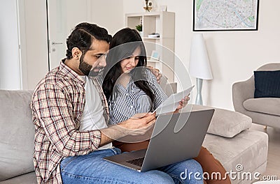 Young indian couple reading bills paying online using laptop at home. Stock Photo