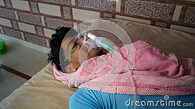 Young Indian farmer taking Emergency Oxygen with Cannula. Severe causes due to Covid in India concept Stock Photo