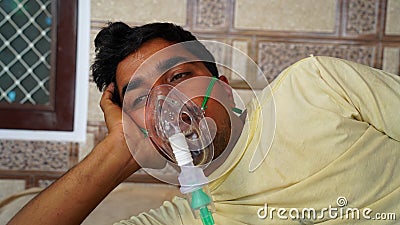 Young man infected with Covid 19 disease. Patient inhaling oxygen wearing mask with liquid Oxygen flow Stock Photo