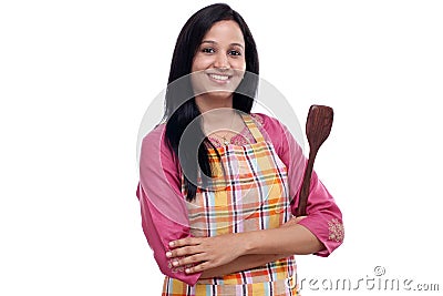 Young Indian woman holding kitchen utensil against white Stock Photo