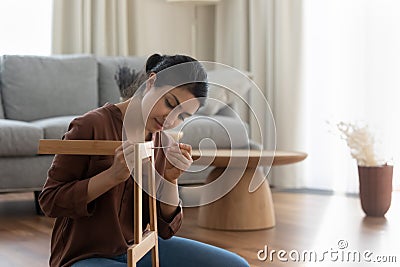 Young ethnic woman gather furniture alone at home Stock Photo