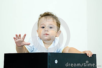 A young infant boy peeking out of a box on a white background Stock Photo