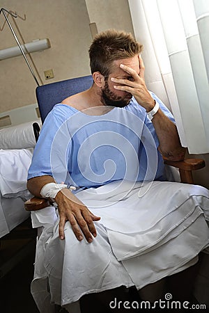 Young injured man crying in hospital room sitting alone crying in pain worried for his health condition Stock Photo