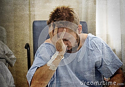 Young injured man in hospital room sitting alone in pain worried for his health condition Stock Photo