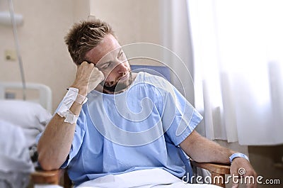 Young injured man in hospital room sitting alone in pain worried for his health condition Stock Photo