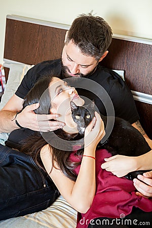 Young inlove couple on the bed with their cats Stock Photo