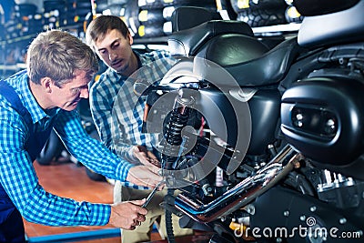 Young interested man customer asking technician about motorcycle Stock Photo