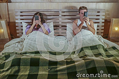 Internet addict couple on bed ignoring each other using social media app on mobile phone flirting and on line dating in relationsh Stock Photo