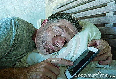 Young internet addict man sleeping on home couch holding mobile phone in his hand in smartphone and social media overuse and onlin Stock Photo