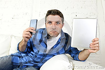 Young internet and technology addict man networking with mobile phone and digital tablet Stock Photo