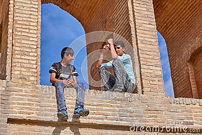Young Iranians sit under arch of bridge Allahverdi Khan, Isfahan Editorial Stock Photo