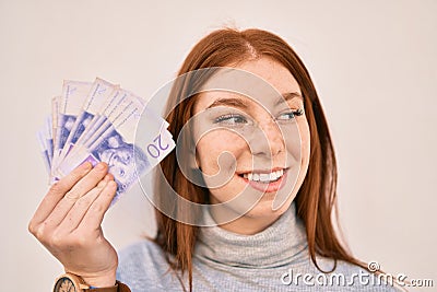 Young irish teenager girl smiling happy holding swedish krone banknotes standing at the city Stock Photo
