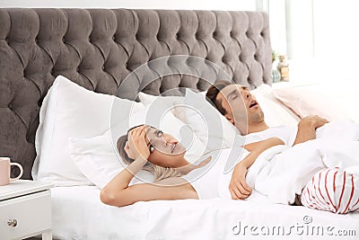 Young irritated woman lying on pillows in bed Stock Photo