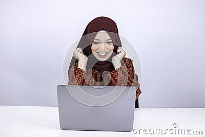 Young Islam woman wearing headscarf is shocked and excited with what she see on laptop on the table Stock Photo