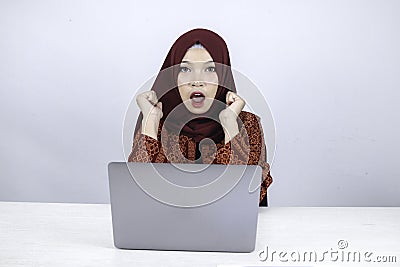Young Islam woman wearing headscarf is shocked and excited with what she see on laptop on the table Stock Photo