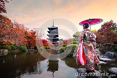 Young Japanese girl traveller in traditional kimino dress standing in Toji temple with wooden pagoda and red maple leaf in autumn Editorial Stock Photo