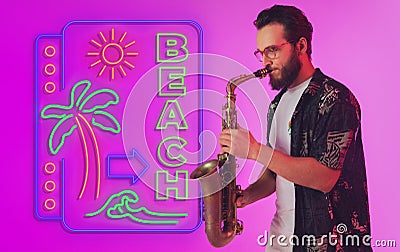 Young jazz musician playing the saxophone in neon light with neon sign Stock Photo