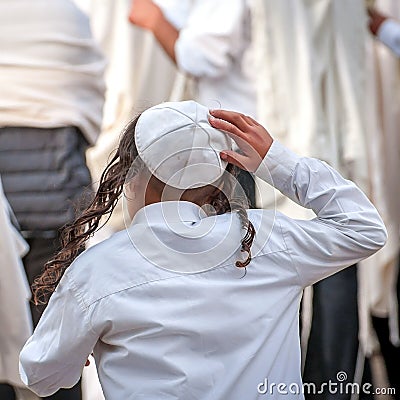 A young Jewish Hasid boy in a traditional headdress of a kippah and with long payos Editorial Stock Photo