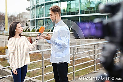 Young journalist interviewing man on street Stock Photo