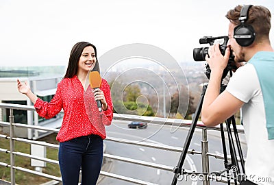 Young journalist and video operator working on street Stock Photo