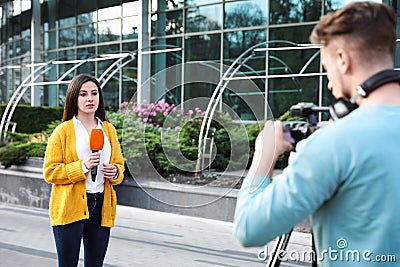 Young journalist and video operator working on street Stock Photo