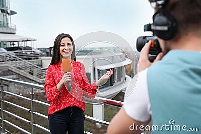 Young journalist and video operator working on street Stock Photo