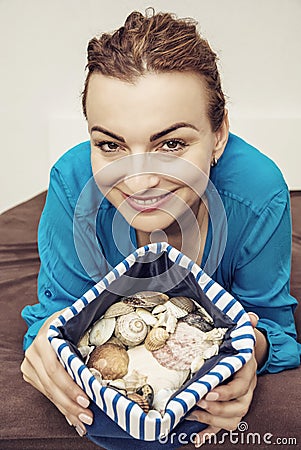 Young joyful brunette with various shells in sailor bag, beauty Stock Photo