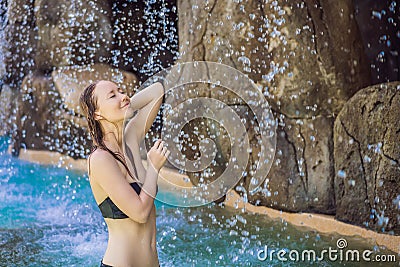 Young joyful woman under the water stream, pool, day spa, hot springs Stock Photo