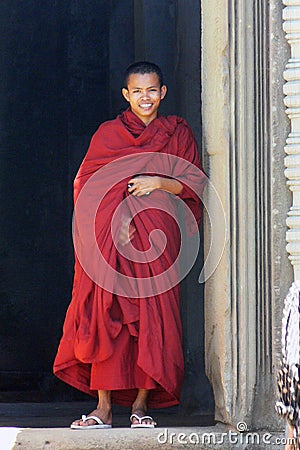 Young Khmer monk smiling in his red dress in Angkor, Cambodia Editorial Stock Photo