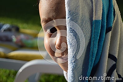 Young kid smiling to the camera after a nice bath in a swimming pool Stock Photo