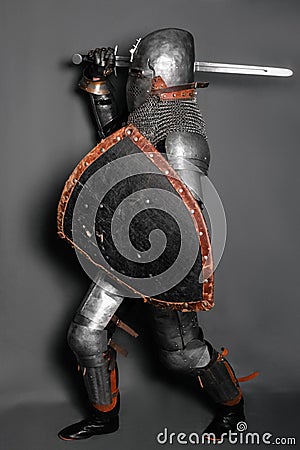 A young knight in medieval armor with a weapon in his hands kneeled Stock Photo