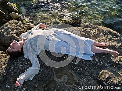 Young Lady Ethic Dress Lying on Sea Rock Stock Photo