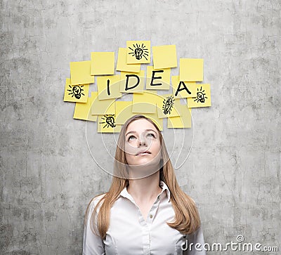 Young lady is looking for new business ideas. Yellow stickers with the word ' idea' and sketches of ' light bulbs ' are h Stock Photo