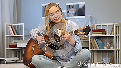 Young lady playing guitar in her room, writing song, dreaming of music career Stock Photo