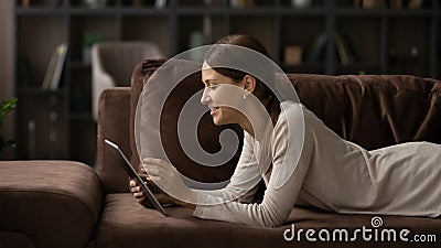 Young lady rest on couch scroll news on tablet online Stock Photo