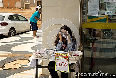 A young lady selling protective face mask outside a shopping center Editorial Stock Photo